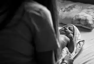 woman in black shirt carrying baby in grayscale photography