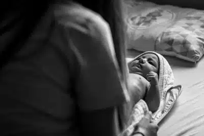 woman in black shirt carrying baby in grayscale photography