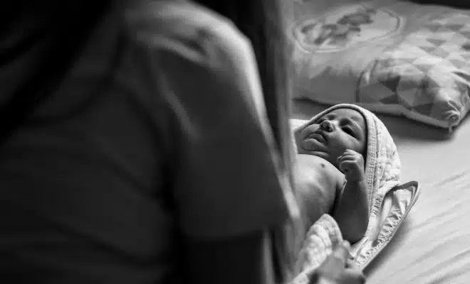 woman in black shirt carrying baby in grayscale photography