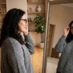 Femme ajustant ses lunettes dans un miroir chez elle