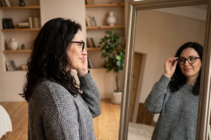 Femme ajustant ses lunettes dans un miroir chez elle