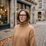 Femme portant des lunettes oversize écaille de tortue en acétate dans une rue pavée en automne, style mode hiver 2026