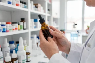Pharmacien tenant un petit flacon en verre ambré dans un laboratoire d'officine