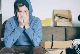 man covering face with both hands while sitting on bench
