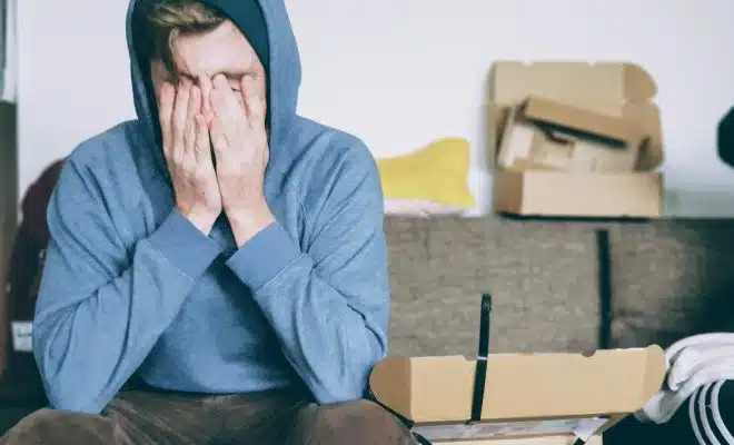 man covering face with both hands while sitting on bench