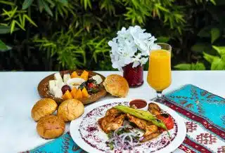bread with vegetable on white ceramic plate beside drinking glass with yellow liquid